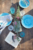 Wooden table set with blue plates in sunshine