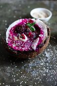 A smoothie bowl served in half a coconut