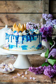 A birthday cake with blue-and-white decorations and a crown