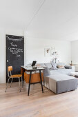 Retro desk and chalkboard behind modern grey sofa