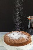 Dusting a chocolate and cherry cake with icing sugar