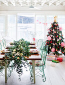 Festive table with flower garland and decorated Christmas tree