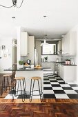 weiße Einbauküche mit Küchentheke und schwarz-weissen Bodenfliesen