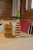 Preserving jar and beer bottle with crocheted covers on table