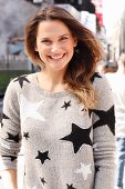 A brunette woman wearing a grey jumper with a star pattern