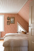 Cat on bed in vintage-style bedroom with sloping ceiling