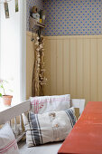 Cushions made from old fabrics on bench in rustic kitchen-dining room