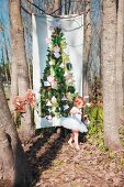 Christmas tree printed on fabric hung between bare trees and little girl wearing white tutu