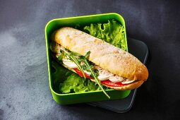 Thunfisch-Sandwich mit Ei und Salat in Lunch-Box vor grauem Hintergrund