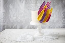 A celebration cake with colourful icing feathers