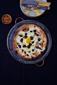 Pizza mit Ei und schwarzen Trüffeln auf Keramikteller (Aufsicht)