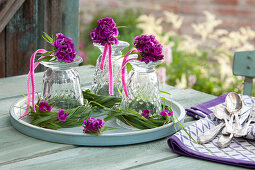 Table decoration made from bunches of Dianthus barbatus (carnations) on inverted glasses in wreaths of grass, placed on a tray