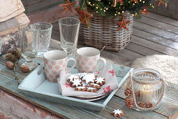 Plate with cinnamon stars and cups on tray, glasses, lantern