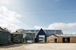 Converted grain silo next to modernised farmhouse with glass entrance