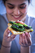 A slice of grilled pizza with rapini, figs, olives and blue cheese