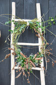 Wreath of Cornus, Ilex and various cones on ladder