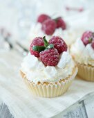 Cupcakes decorated with whipped cream, meringue pieces and raspberries