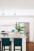 Kitchen island with bar stools, stainless steel fridge combination in the background