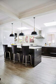 Mittelblock mit Barhockern vor Küchenzeile in offener Küche mit Porzellan-Bodenfliesen in Holzoptik