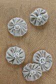 Small fabric rosettes with beads on piece of painted cardboard