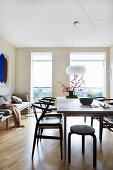 Black chairs around dining table in front of floor-to-ceiling windows