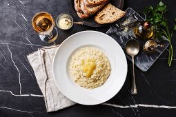 Risotto mit Parmesan auf Teller und dunklem Marmortisch (Aufsicht)