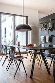 Black, modern dining table in front of hook rails mounted on grey wall