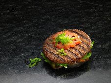 A grilled hamburger on a black bread roll