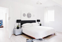 Double bed with bedside cabinets below artwork on wall in bright bedroom