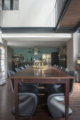 Black designer chairs around wooden table below gallery level