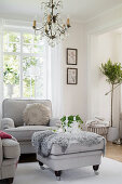 Grey fur blanket on ottoman used as coffee table in front of armchair