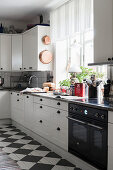 Panelled cupboards and chequered floor in white kitchen
