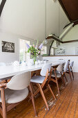 Various retro chairs with pale upholstery at long dining table