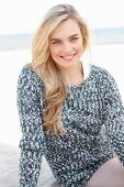 Junge blonde Frau in grau-weißem Strickpullover