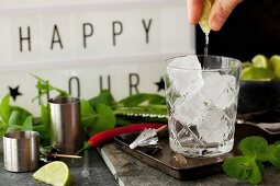 A person squeezing lime into a glass