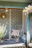 Alter Schaukelstuhl aus Holz im Gartenhäuschen mit tapezierter Wand