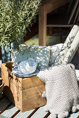 Crockery, cushions and roll of wallpaper in wooden crate