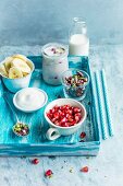 Joghurt mit Granatapfelkernen, Bananenscheiben, Pistazien und Milch