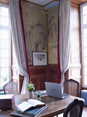 Wooden table in lounge with wainscoting and murals on walls