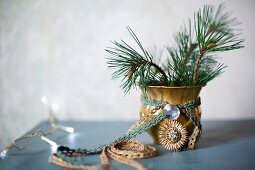 Brocade ribbons tied around gilt vase of fir branches