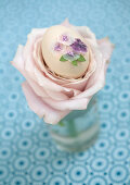Egg decorated with glittery flowers and nestled in centre of rose