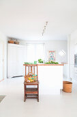 Basket on chair in front of white kitchen island in front of white corner cabinet