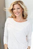 A blonde woman wearing a white long-sleeved top