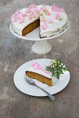 A cake decorated with edible lemon geraniums, sliced