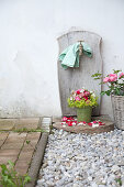 Rosenstrauss mit Frauenmantel und Obstblüten und Blumenkorb mit Rosen am Brunnen