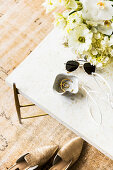 A bowl of jewelry, sunglasses and a bouquet of white flowers on a coffee table