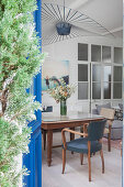 Dining table with armchairs and designer ceiling light in open-plan interior