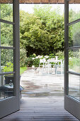 Table, chairs and dog on terrace surrounded by summery garden