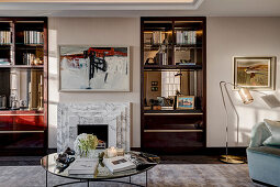 View across coffee table to fireplace with marble surround flanked by integrated shelves