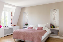 Pink blanket on bed flanked by niches instead of bedside tables